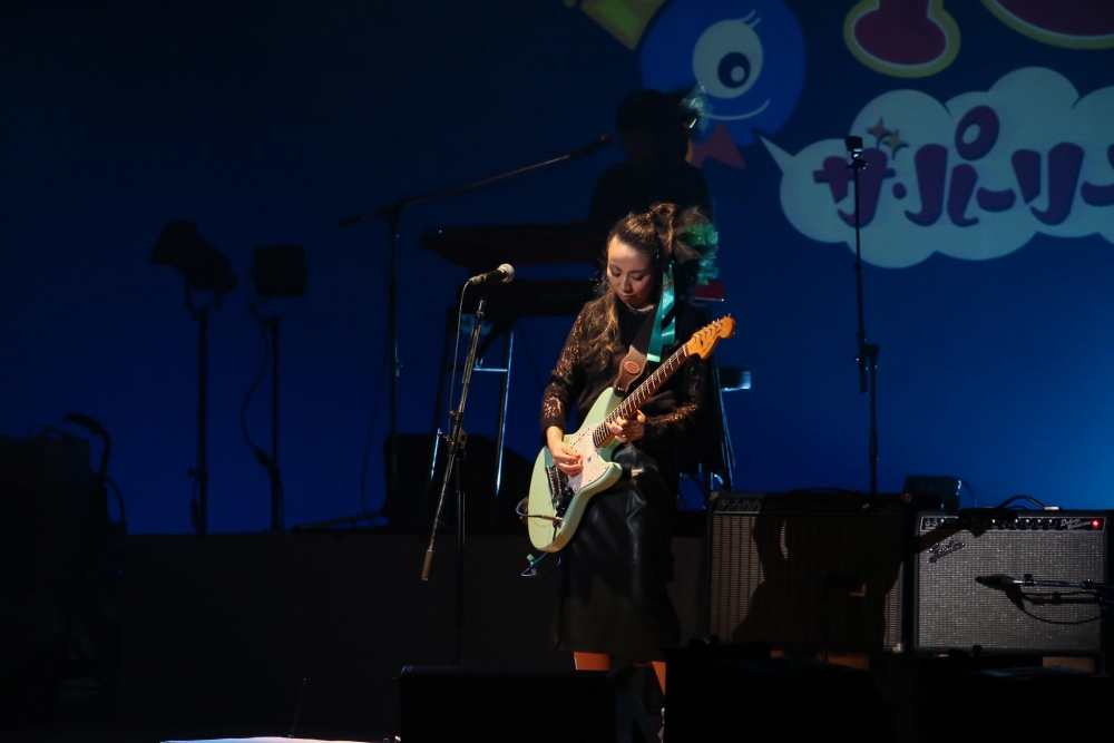 ステージでギターを弾くナンシーさん。(ナンシーさん提供。2019年11月撮影、小田原市民会館 にて)